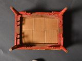 a small red wooden chair with a brown mat on it