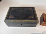 a black box with a gold border and a wooden box with a black lid