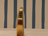 a gold ring sitting on top of a table next to a blue and white striped wall