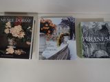 trois livres sont alignés sur une étagère devant une fenêtre