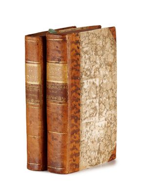 two old books sitting on top of each other on a white surface