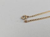 a gold necklace with a chain on a white surface