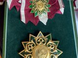 une médaille d'or accompagnée d'un ruban vert et d'un ruban rayé rouge et blanc