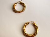 two pairs of gold toned hoop earrings on a white surface