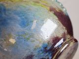 a close up of a hand holding a blue and green vase