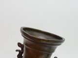 a hand holding a bronze vase with a dragon on it