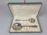 a silver spoon and spoon rest in a green case