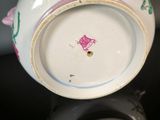 a white vase with pink flowers on it on a black surface
