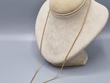 un collier en or sur une tête de mannequin, muni d'une chaîne en or