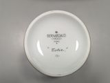 a close up of a plate on a table next to a stack of plates