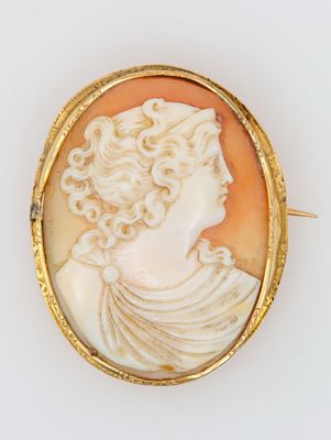 Une broche plaquée or représente le profil d'une femme.