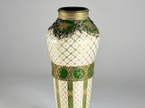un vase vert et blanc posé sur une surface blanche