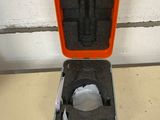 an orange case with a black handle on the floor next to a white wall