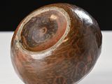 a brown and black vase sitting on a white table