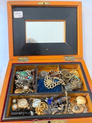 a wooden box filled with assorted jewelry on a white surface
