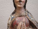 a wooden statue of a woman with a praying hand