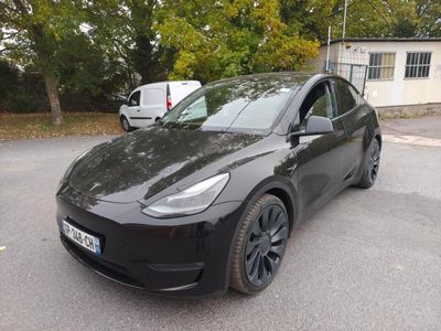 un SUV Tesla noir garé sur un parking à côté d'une camionnette blanche