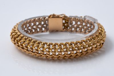 gros plan d'un bracelet en or sur une surface blanche