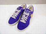 purple sued sneakers with white laces and a gold buckle