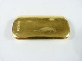 une barre d'or posée sur une surface blanche