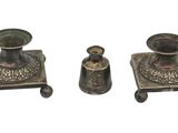 three antique silver candlesticks and a candle holder on a white background