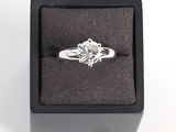 une image représentant une bague en diamant dans un écrin noir sur fond blanc
