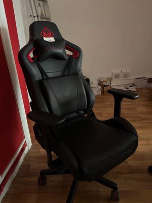 une chaise de bureau noire avec une assise rouge, dans un coin de la pièce