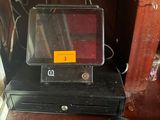 une caisse enregistreuse noire posée sur un bureau en bois