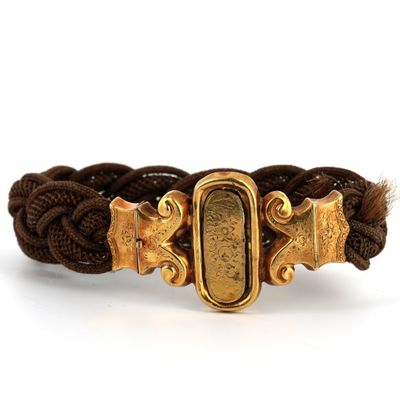 un gros plan sur un bracelet tressé muni d'un fermoir doré