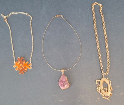 three necklaces with different colored stones are displayed on a blue surface
