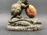 statue of a mouse eating a nut on a rock