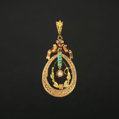 a gold and emerald pendant with a bird on it