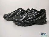 La chaussure de course New Balance 990 est noire et comporte une bande argentée.
