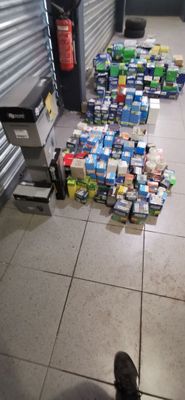 une personne debout sur le sol, devant une pile de canettes de soda
