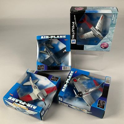 trois boîtes contenant des avions miniatures, posées sur une surface blanche