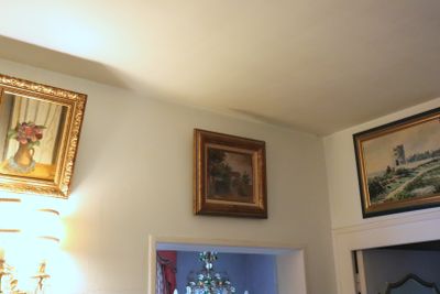 a picture of a living room with paintings on the wall