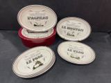 four red and white dishes with labels on them sitting on a black surface