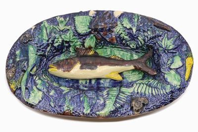 une assiette sur laquelle est posé un poisson, posée sur un fond blanc