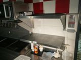 plan de travail en acier inoxydable dans une cuisine professionnelle aux murs à carreaux rouges et blancs