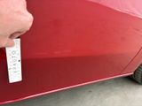 a man that is opening the door of a red car