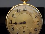 a close up of a gold pocket watch on a table
