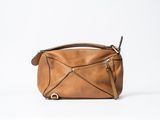 the small leather bag is made with a cross - body strap and a zipper closure