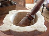 un mortier muni d'un manche en bois, posé dans un saladier sur une table