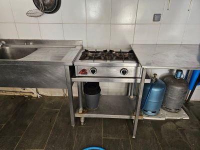 a kitchen with a stove, sink, and a pot on the floor