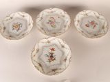 quatre assiettes ornées de motifs floraux sont disposées sur une surface blanche