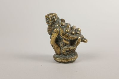 figurine en laiton représentant un singe tenant un poisson, sur fond blanc