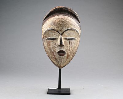 a wooden mask on a stand with a gray background