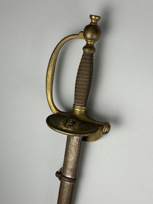 une vieille épée avec une poignée en or sur une surface blanche