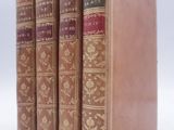 three old books are lined up on a white surface