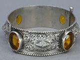 a close up of a silver bracelet with two yellow stones on it